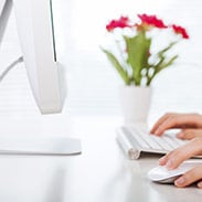 Close up of a user with one hand on the keyboard and one hand on a mouse