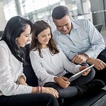 Man, woman, and girl looking at an iPad together